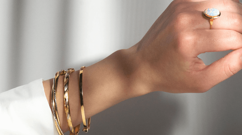 gold bracelets and premium gold ring on woman hand in shadows