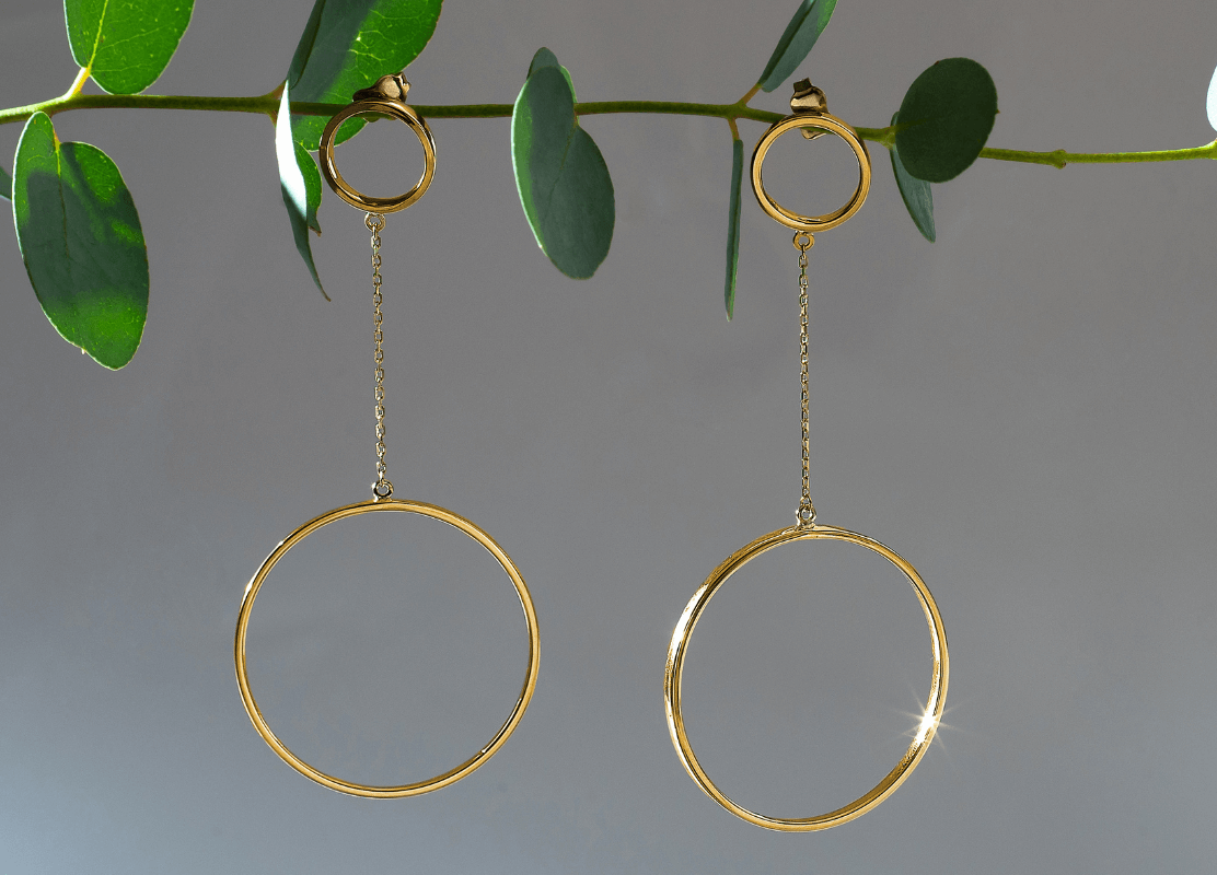  Zlatne karike naušnice koje elegantno vise s grane u jedinstvenoj prezentaciji nakita.