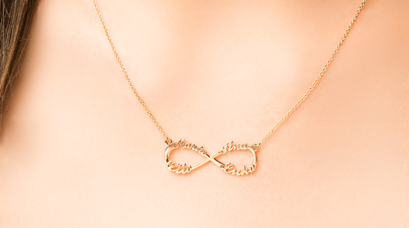 personalized gold necklace with infinity pendant with four names on it on womans neck