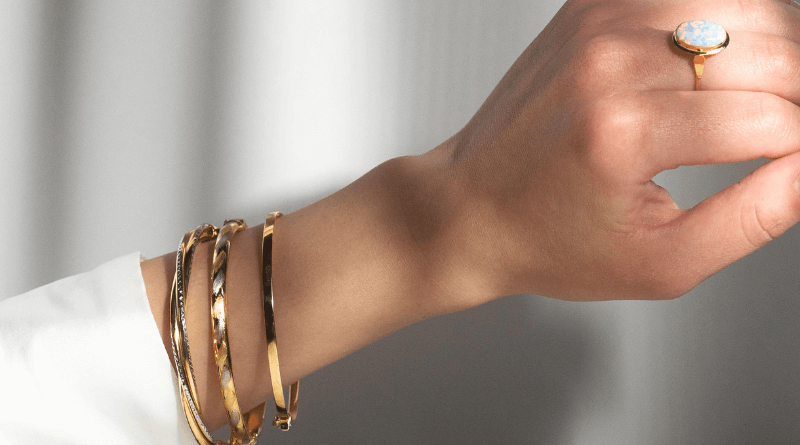 layering of 14kt gold jewelry in white and yellow gold on woman hand