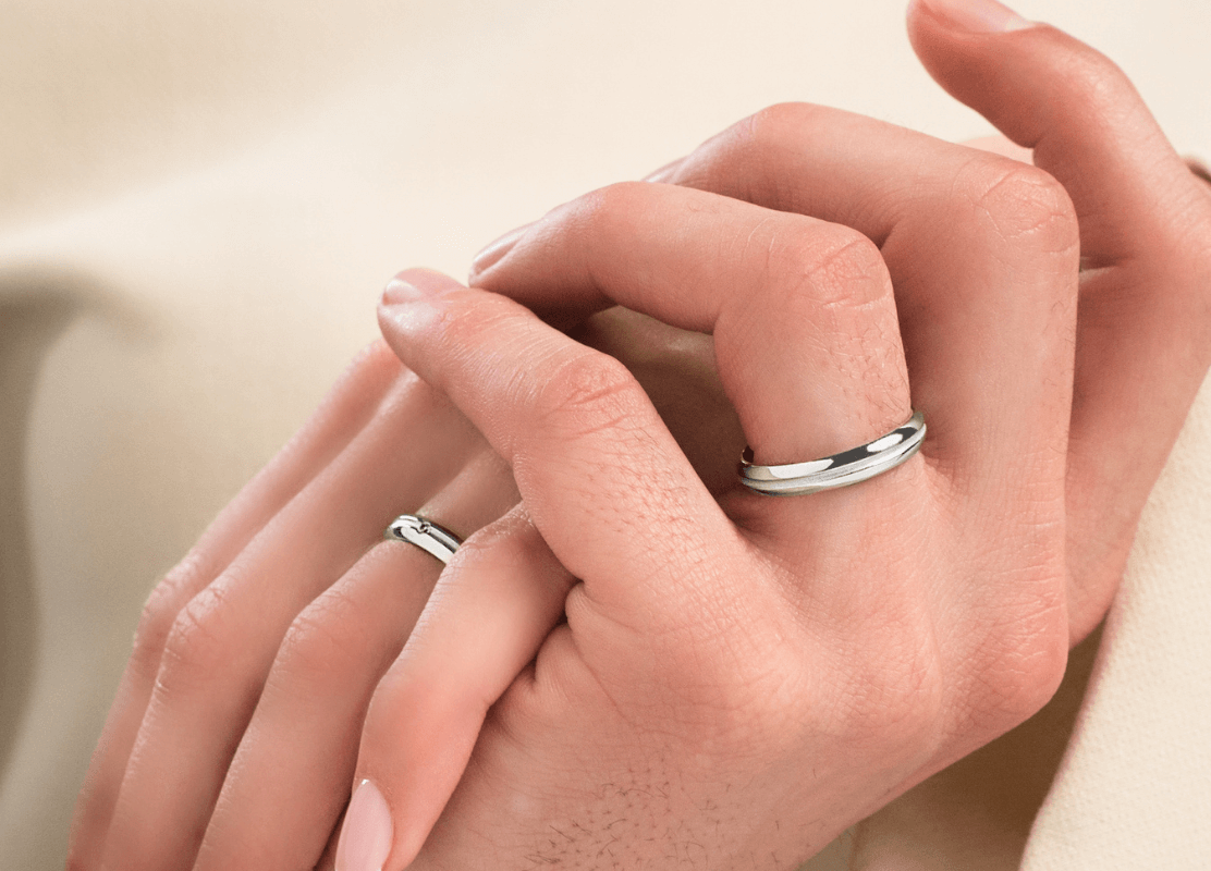 Zlatno vjenčano prstenje na rukama para koji se drži za ruke.