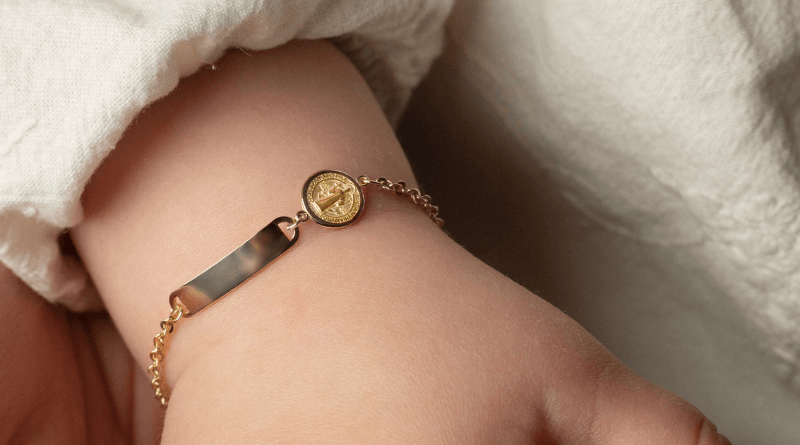 gold bracelet baby child with sacred motif on baby hand