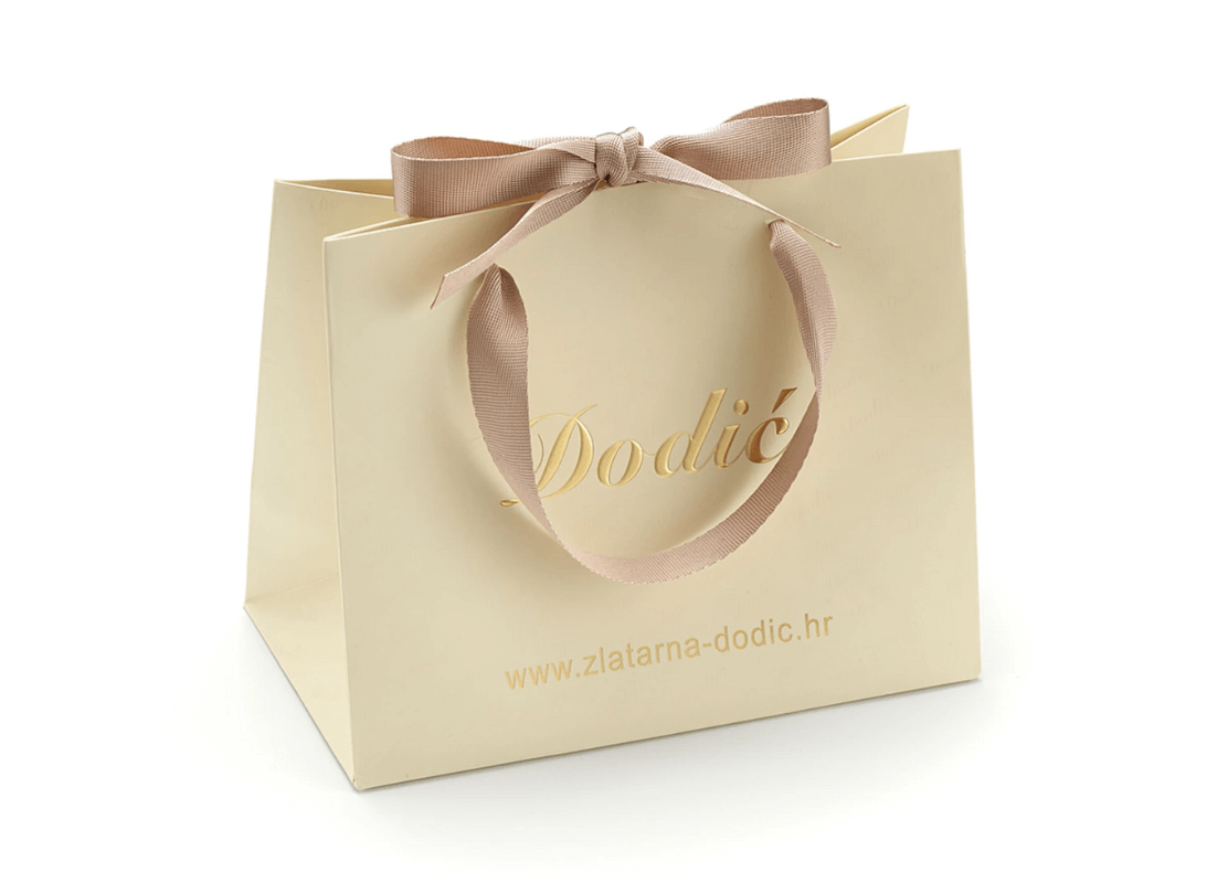 Bež papirna vrećica Dodić ukrašena nježnom ružičastom vrpcom koja daje dašak elegancije i šarma.
