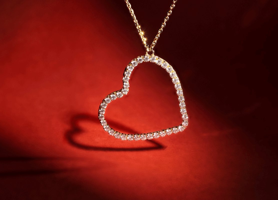  Svjetlucavi dijamantni privjesak u obliku srca na živahnoj crvenoj pozadini zrači ljubavlju i elegancijom. Motiv srca.