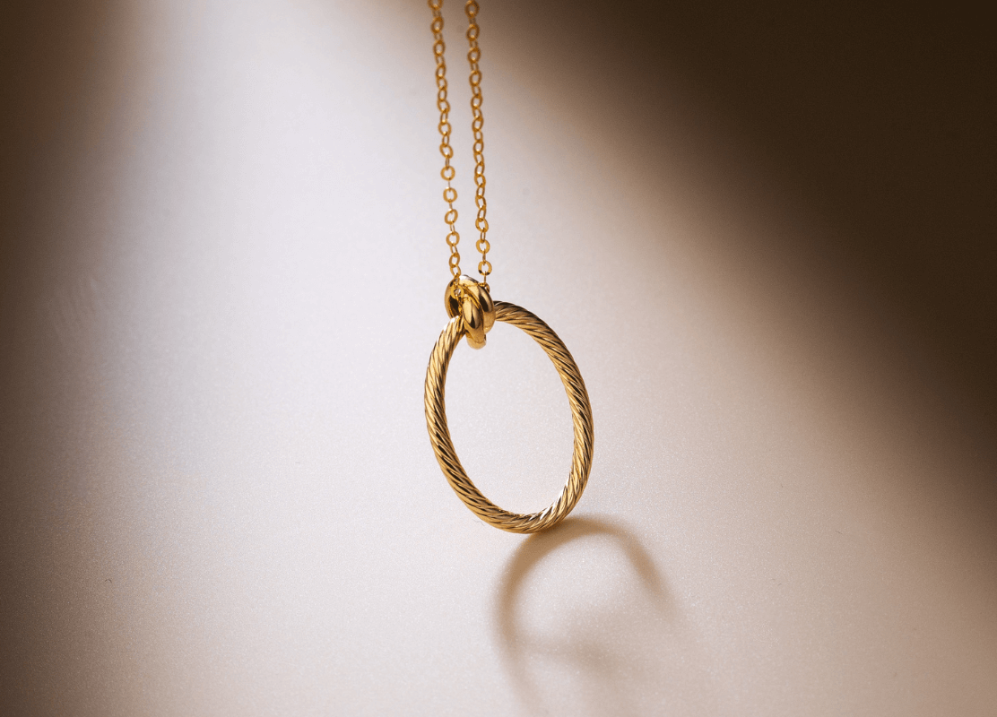 Prekrasna zlatna ogrlica s okruglim privjeskom, savršena za dodavanje daška elegancije svakoj odjeći.