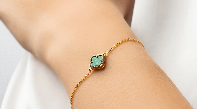 gold earrings with clover motif with green malachite on woman wrist