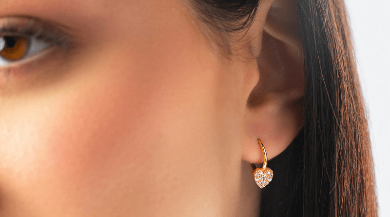 gold earrings with heart motif on womans ear