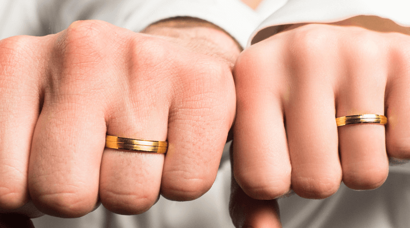 gold wedding rings on hands of newlywed married couple