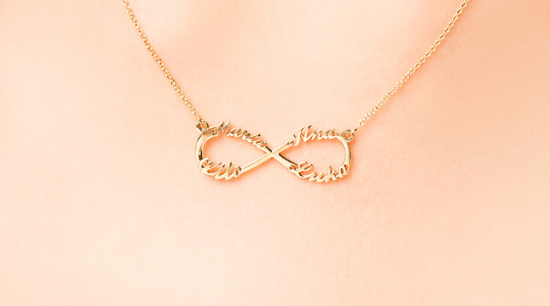 personalized necklace with four names in infinity shape made of 14kt gold on womans neck