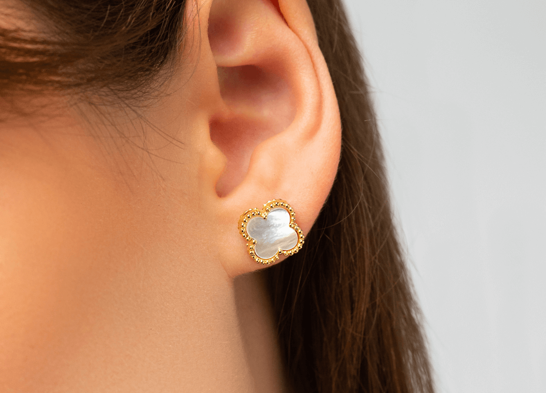 woman wearing gold earrings clover