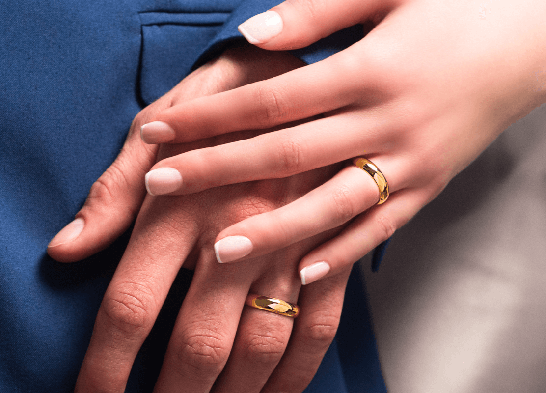 zlatno vjenčano prstenje od žutog zlata na prstenjaku uz plavo odijelo