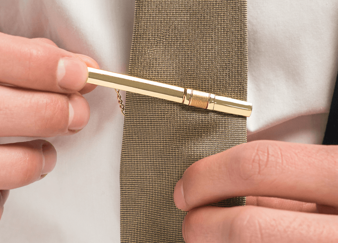 a man with a tie and a gold tie pin