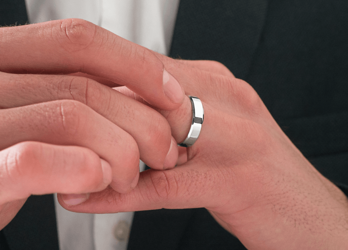zlatni vjenčani prsten od bijelog zlata na muškoj ruci uz crni smoking
