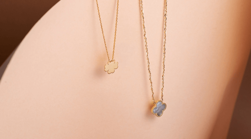 two clover gold necklaces on peach surface